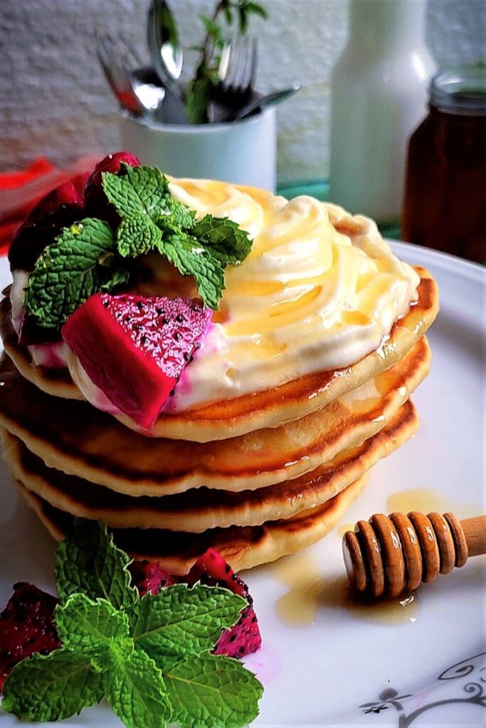 Old fashion pancake recipe decorate with dragon fruit, honey, whipped cream on a plate