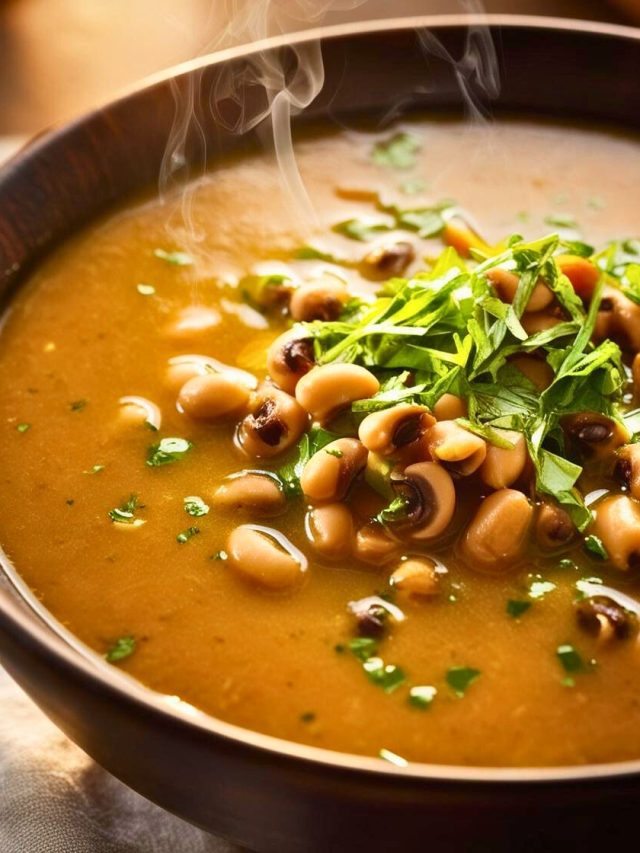 A steaming bowl of black-eyed pea soup garnished with fresh parsley, served with crusty bread on the side.